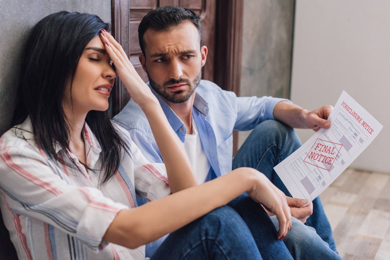 Stressed woman with husband holding document with foreclosure and final notice lettering on floor in